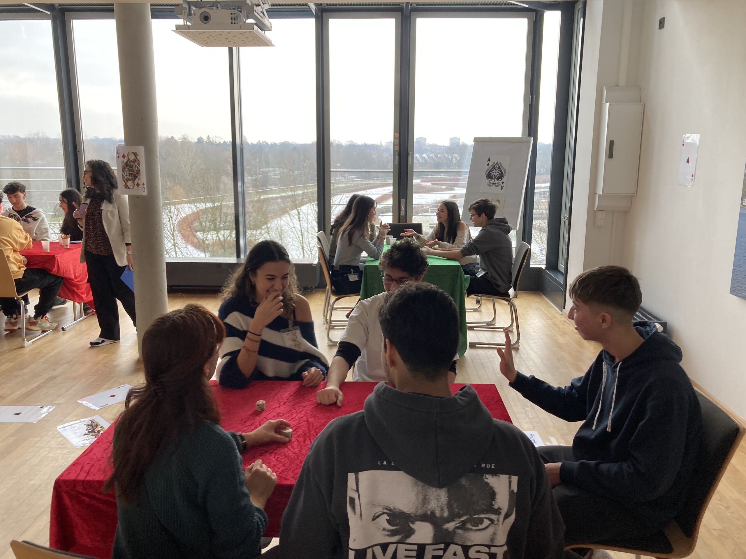 Jugendliche sitzen in einem Seminarraum ein Tischen und spielen Spiele.